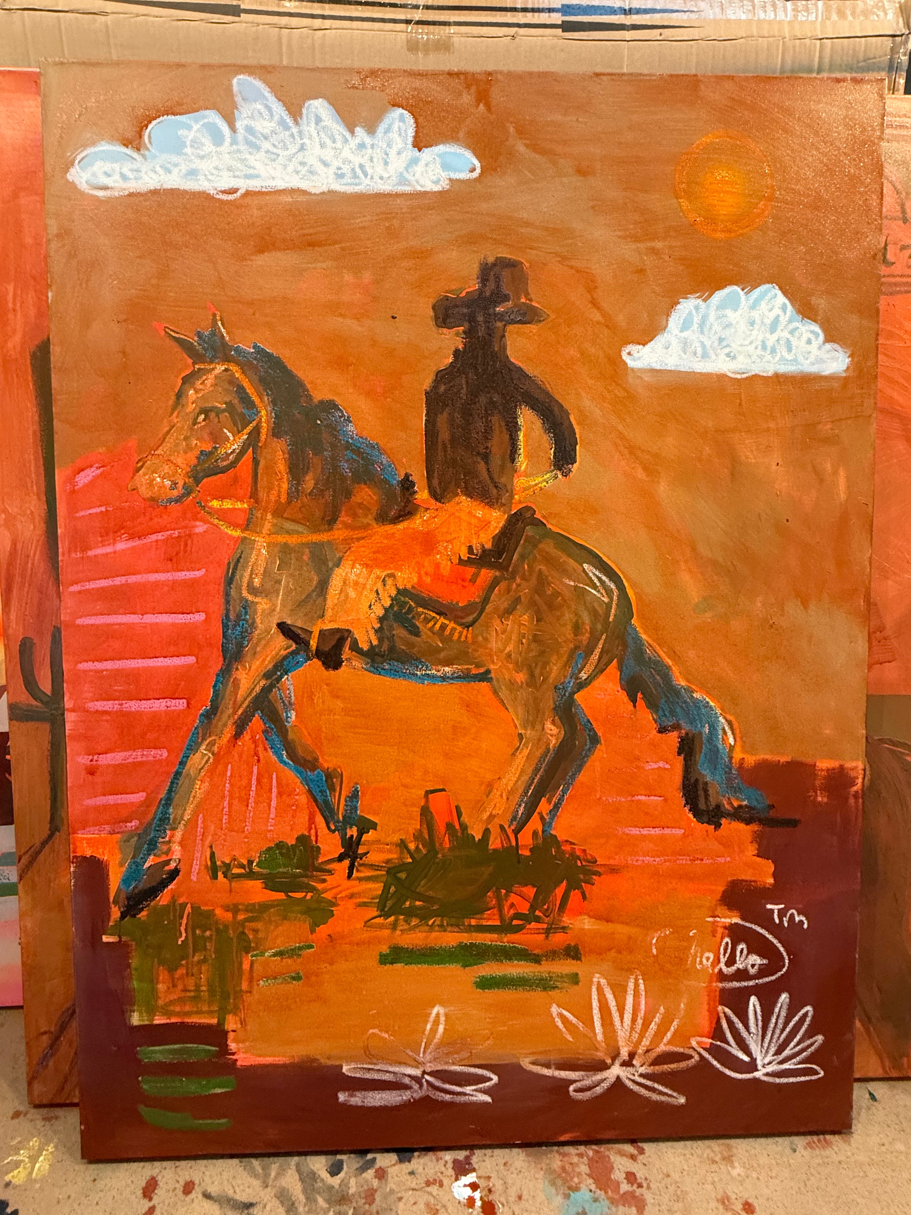 Painting of a cowboy on a horse with a desert landscape and cacti.
